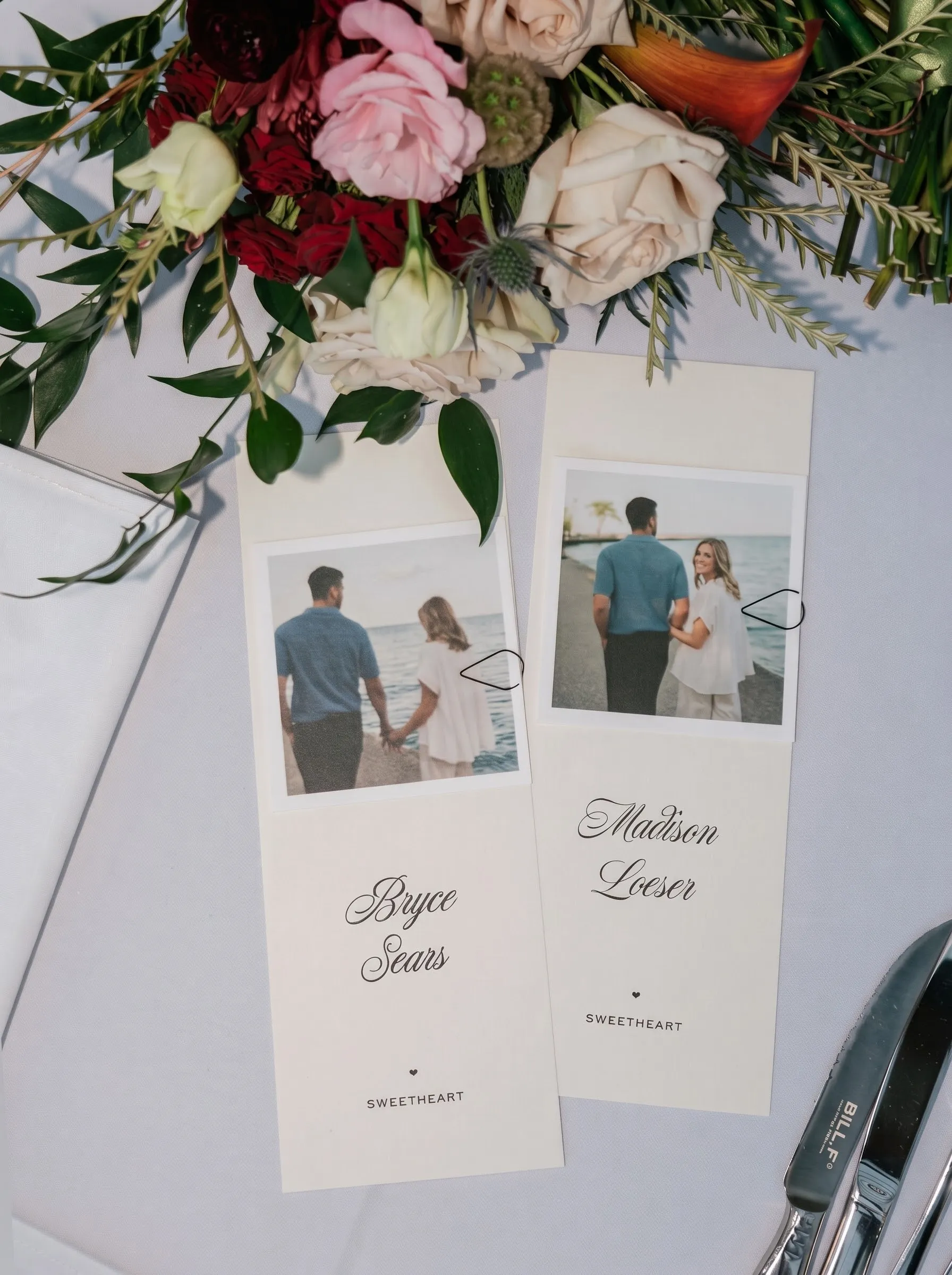 The couple's place cards at the sweetheart table, among flowers and silverware